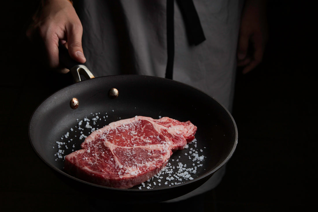 person cooking meat on black pan