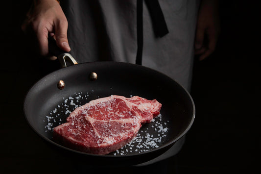 person cooking meat on black pan